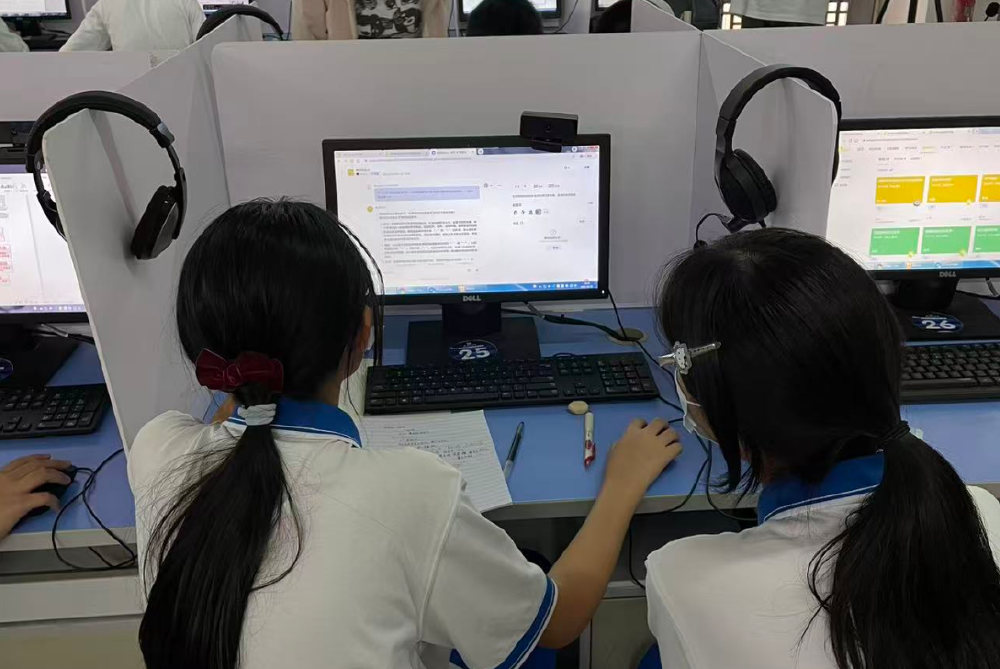 两名学生对着屏幕与智能体对话,桌上摊着手绘方案