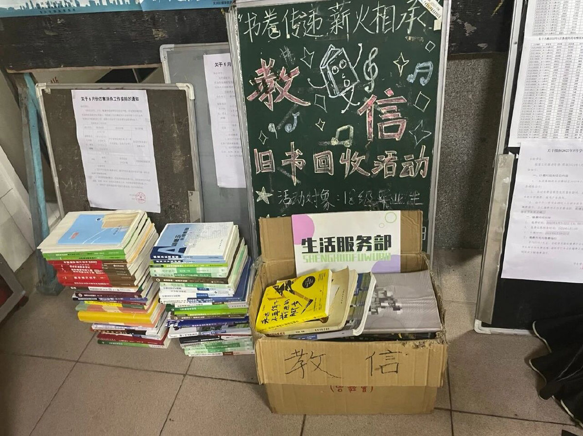 2021 年旧书回收活动现场,黑板手写海报与分类堆放的旧书
